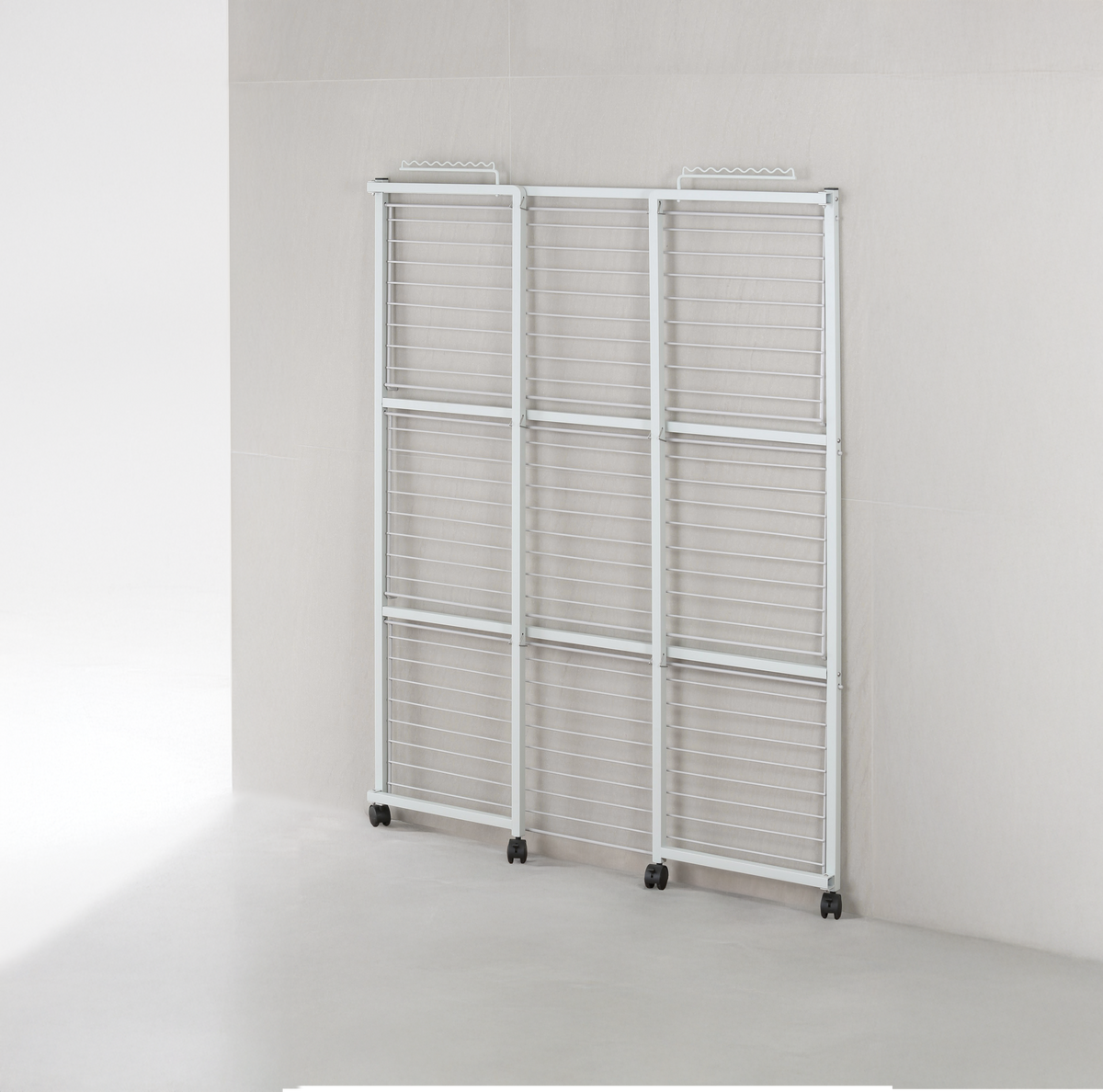 White 3-tier clothes airer folded to 6cm and standing flat against a laundry wall