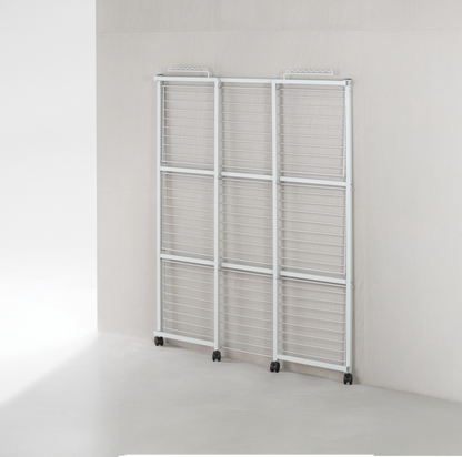 White 3-tier clothes airer folded to 6cm and standing flat against a laundry wall