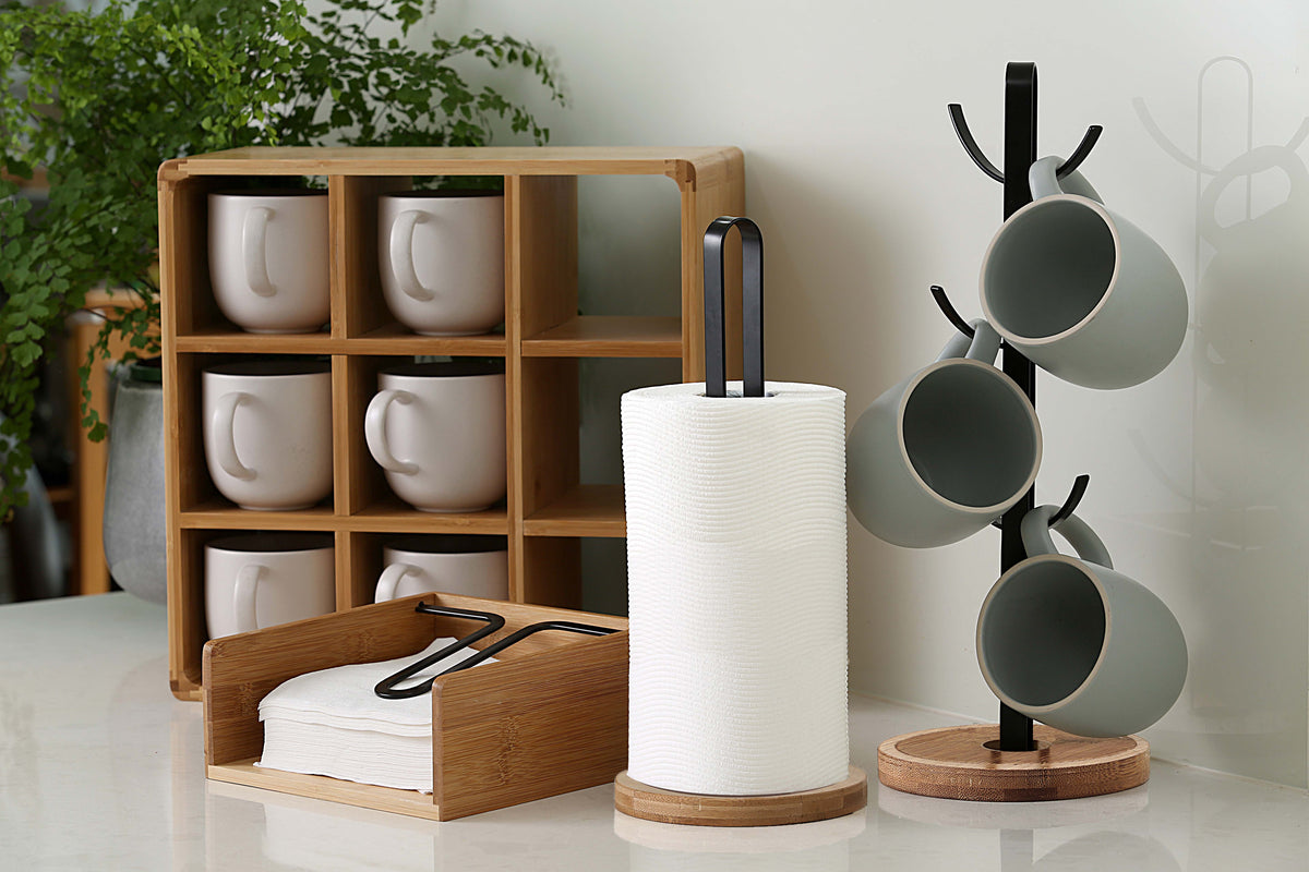 Bamboo napkin holder on a kitchen bench holding a stack of white napkins under the black metal arm